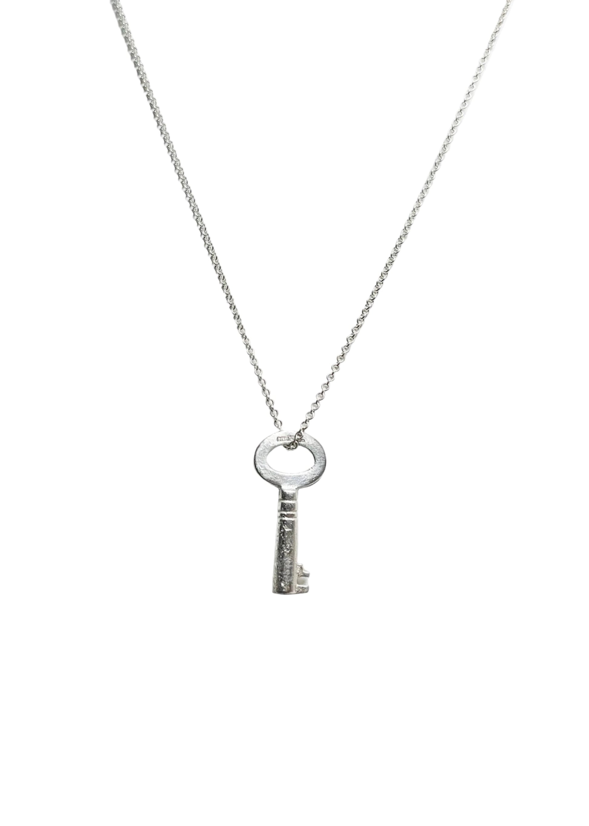Silver key pendant necklace on a white background