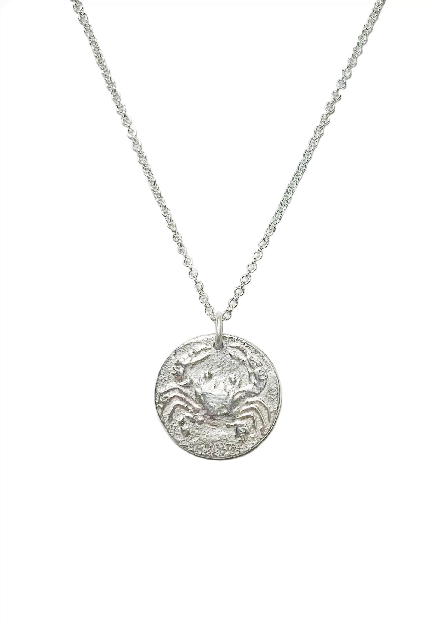 Silver necklace with a round pendant depicting a crab for the zodiac astrological sign of Cancer on a white background